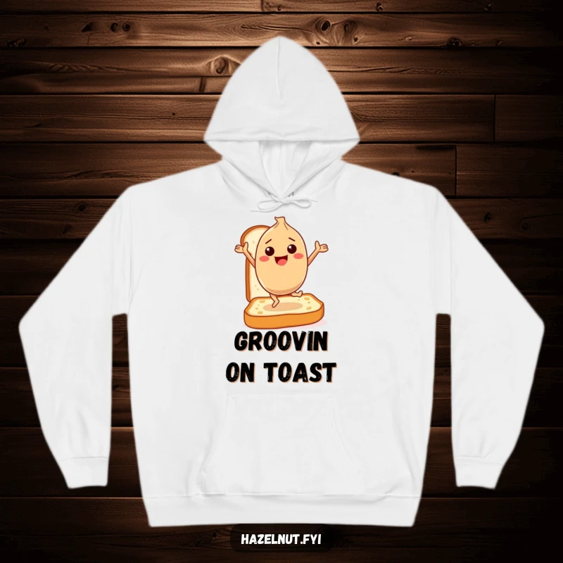 Funny Hoodie: A happy hazelnut character dances gleefully on a slice of toast, offering warmth and a humorous breakfast celebration.